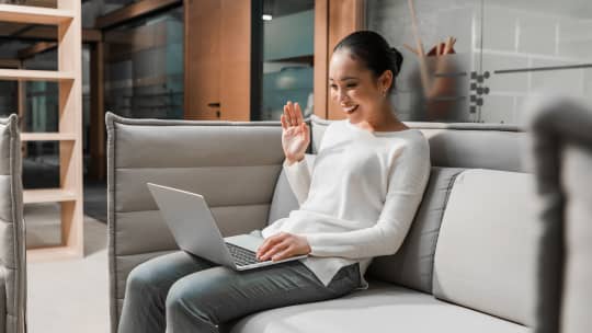 joyful woman waving into laptop