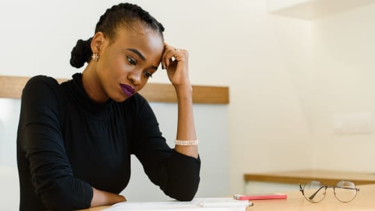 A woman looks down at a paper while looking stressed