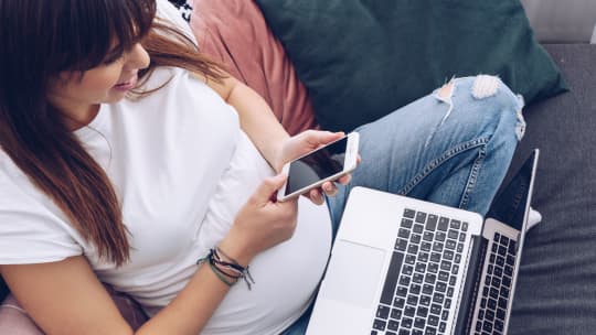 pregnant woman on a computer and her phone 