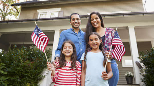 family of four with children holding American flag