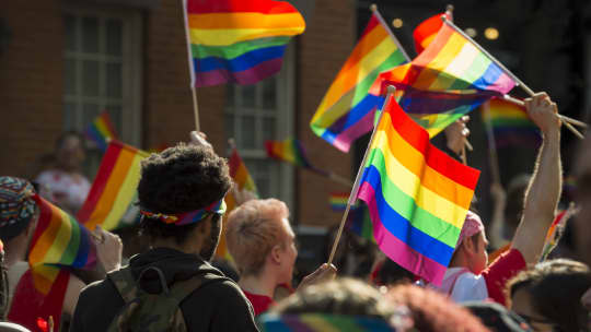 marchers waving pride flags at a parade