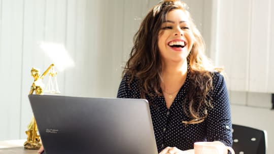 professional woman sitting at a computer laughing
