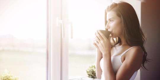 Woman drinking coffee and looking out window