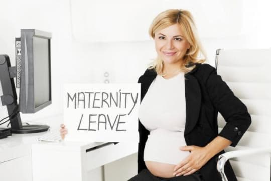 pregnant woman holding maternity leave sign